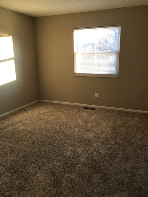an empty room with a window and carpet