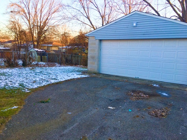 a white garage with a blue roof on a driveway