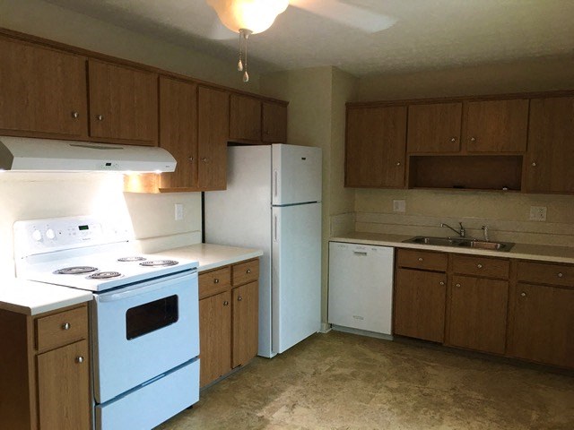 an empty kitchen with white appliances and wooden cabinets