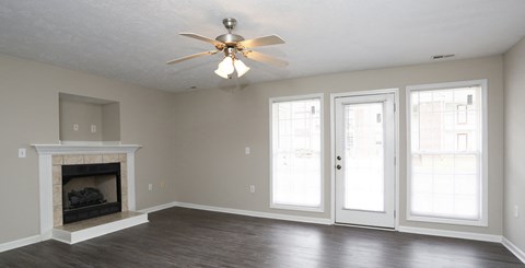 an empty living room with a fireplace and a ceiling fan