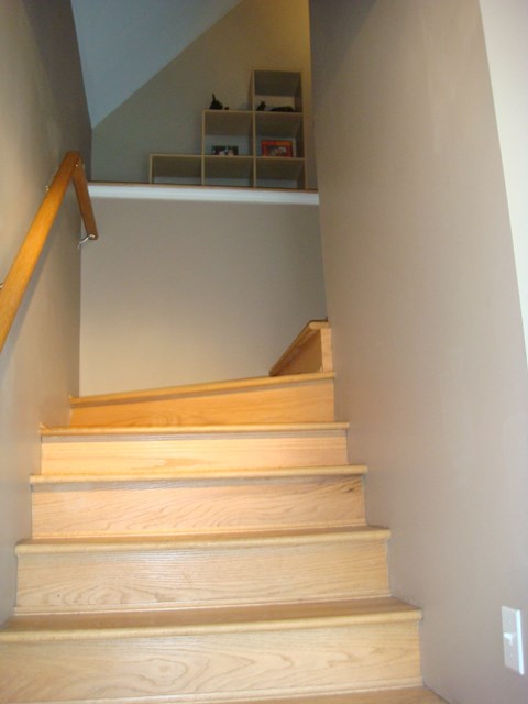 a flight of stairs in a home with white walls and wooden railings
