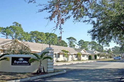a neighborhood of houses with a sign and a palm tree