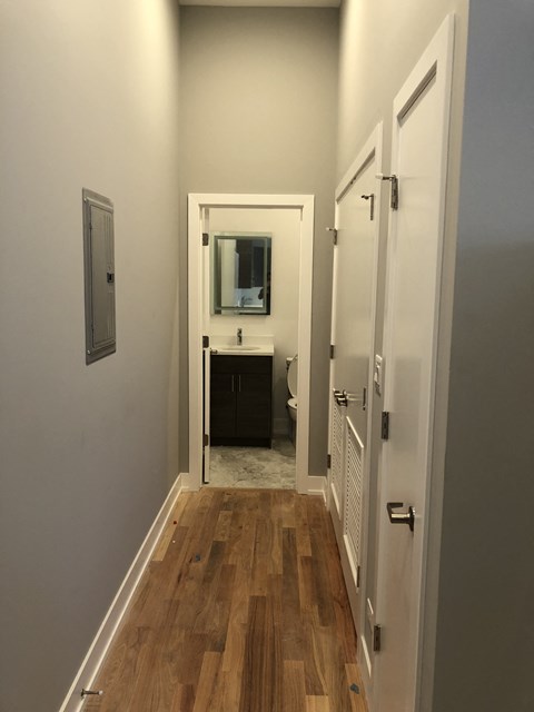 a small hallway with a door to a bathroom with a sink and a mirror