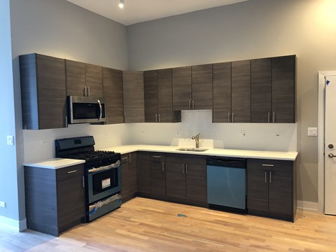 a kitchen with dark cabinets and a stove and a sink