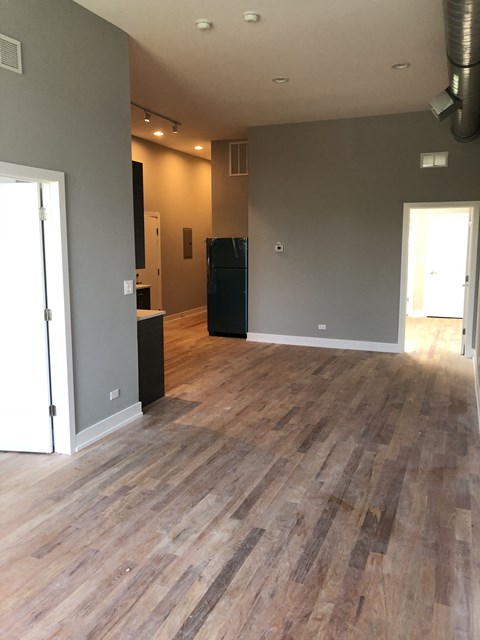 an empty living room with a wooden floor and grey walls