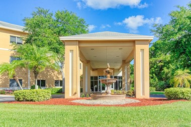 lushly landscaped entrance with tiered fountain