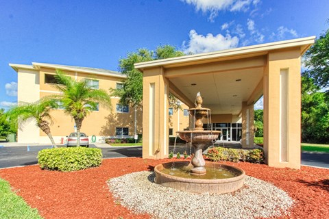 covered drive with tiered fountain and neat landscaping