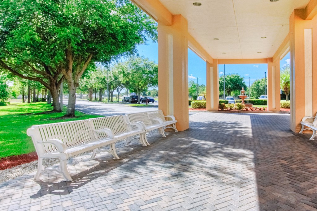 covered entrance with several benches surrounded by landscaping