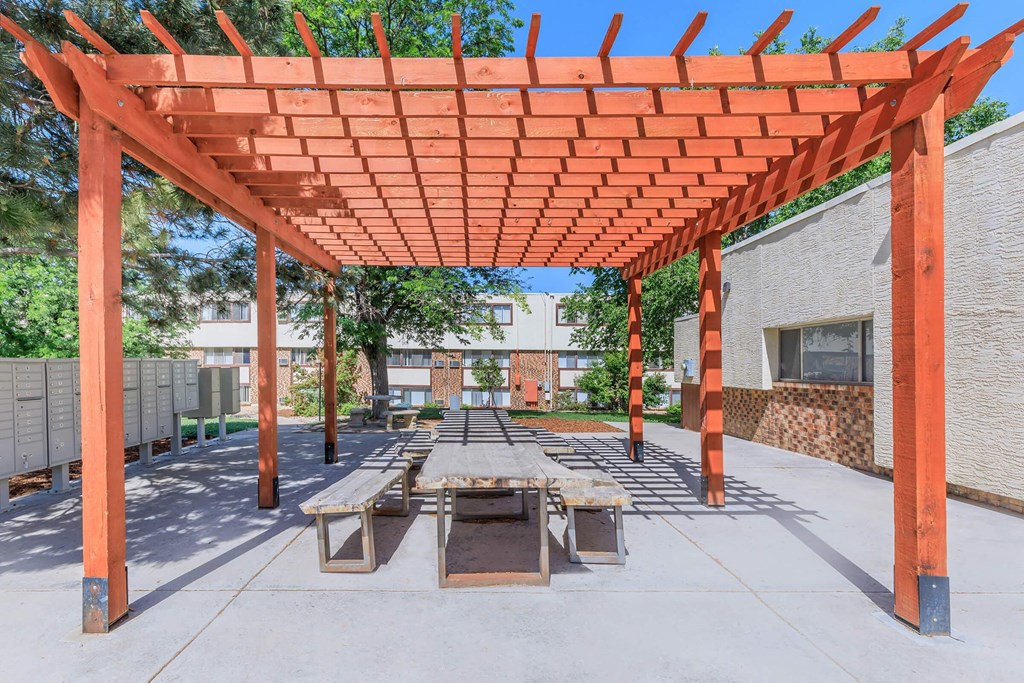 a picnic area with benches under a wooden pavilion