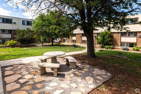 a picnic table sitting under a tree in front of an apartment building