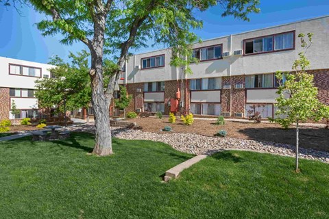 the exterior of an apartment building with grass and trees