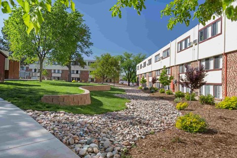 a courtyard with grass and rocks in front of an apartment building