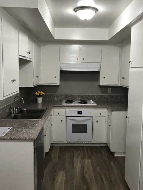 A kitchen with white cabinets and a wooden floor.