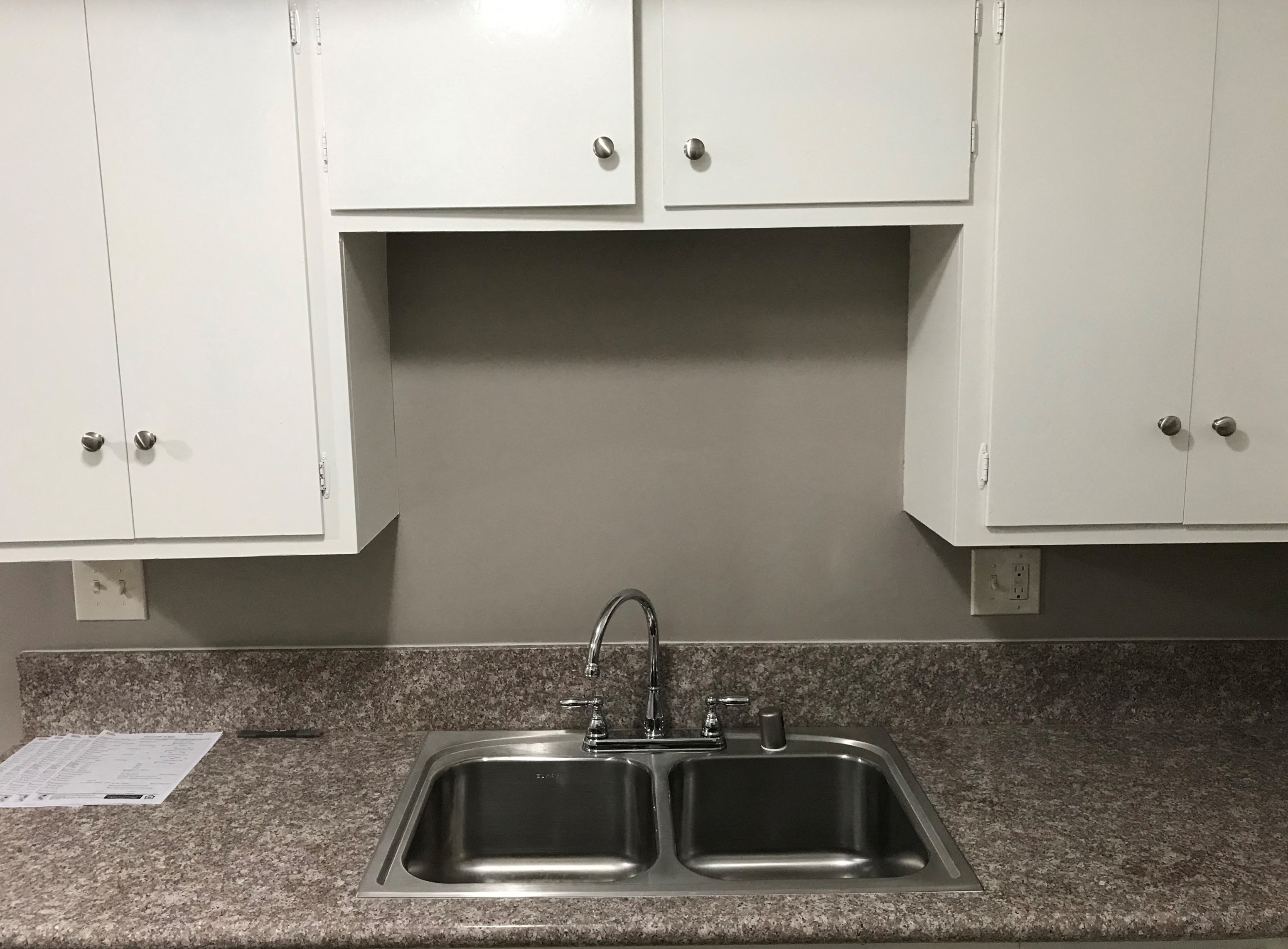 A kitchen with a granite countertop and a double sink.