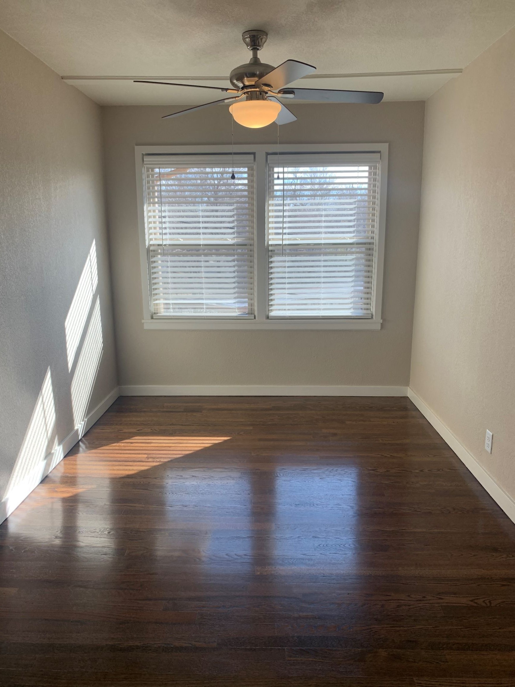 an empty room with a ceiling fan and a window