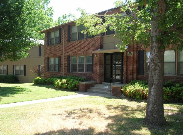 a red brick house with a tree in front of it