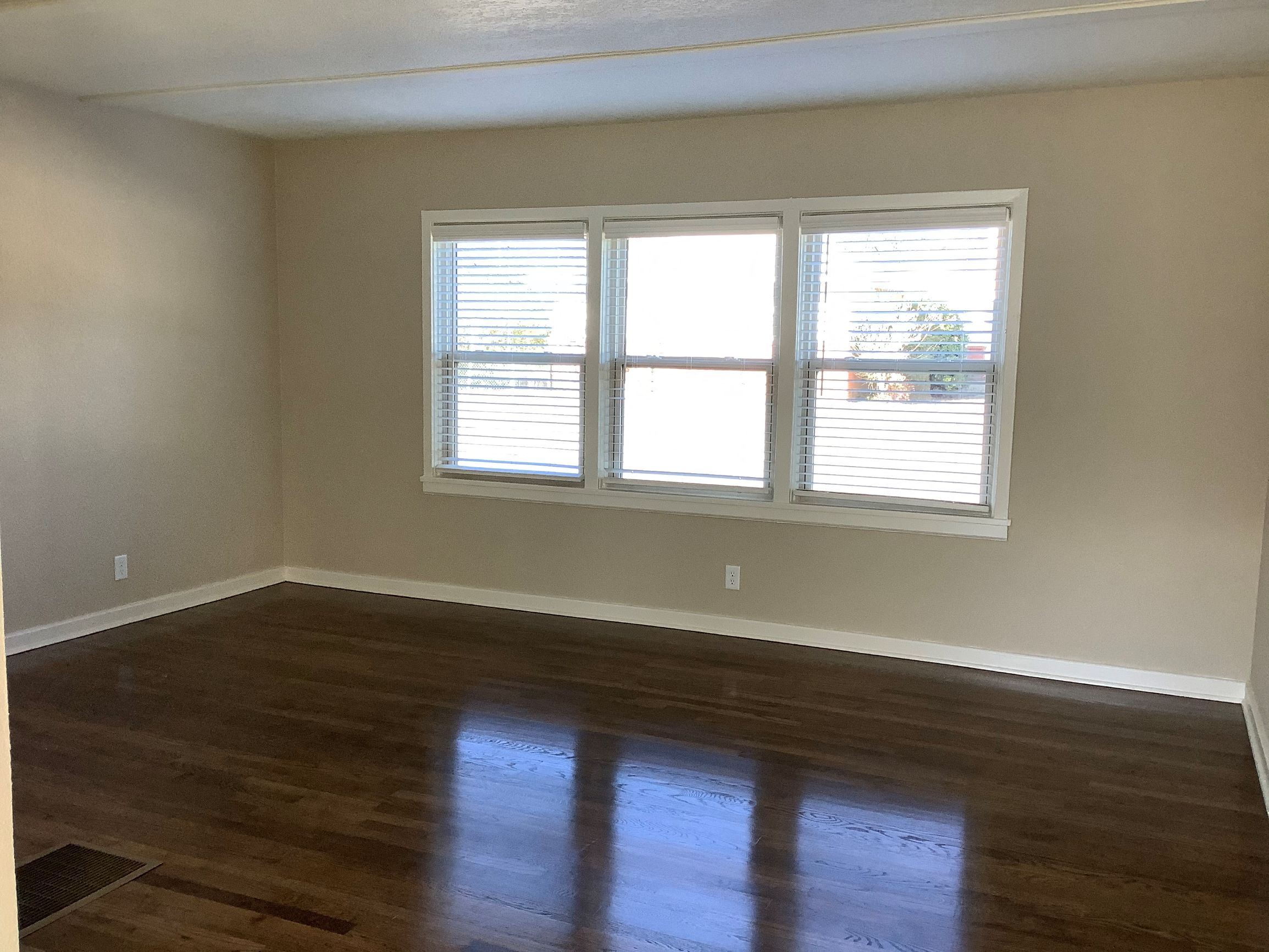 an empty living room with wood floors and a window