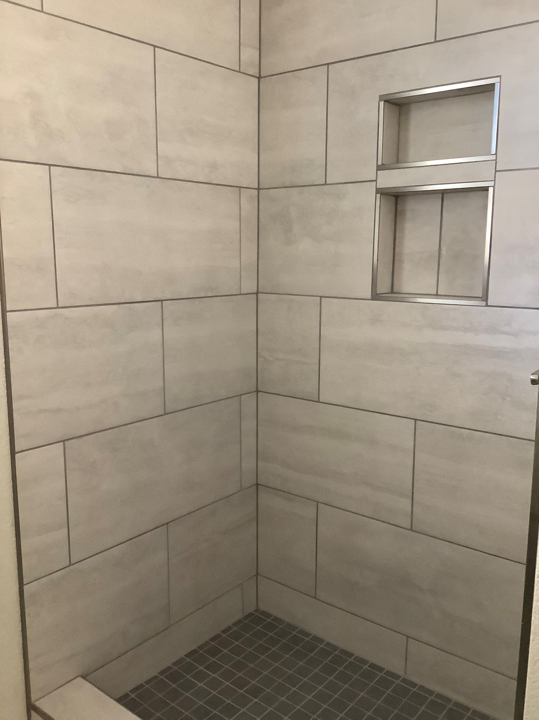 a small shower with tiled walls and a window
