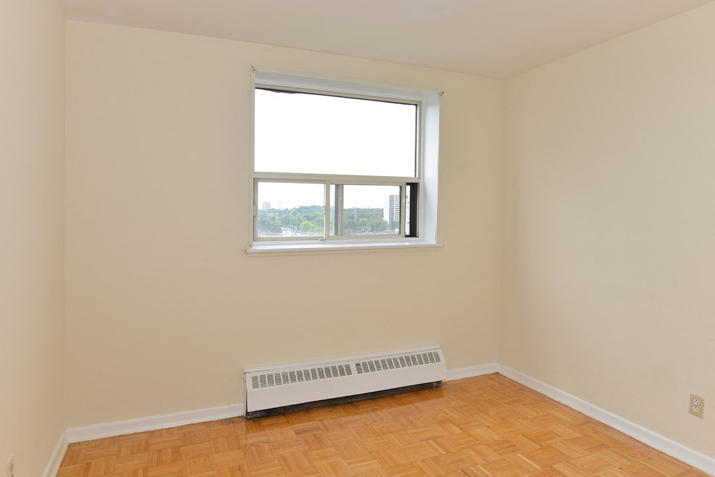 an empty room with a window and a wood floor