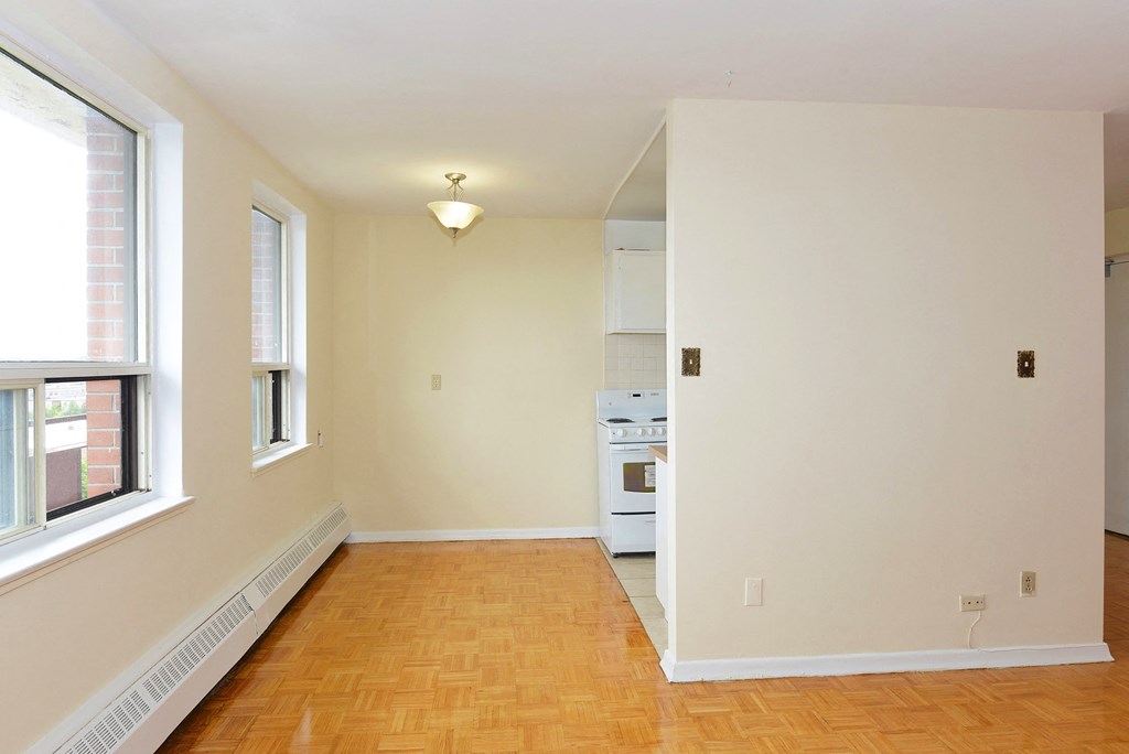 an empty living room with two windows and a wood floor