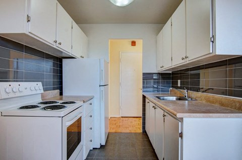 an empty kitchen with white appliances and white cabinets