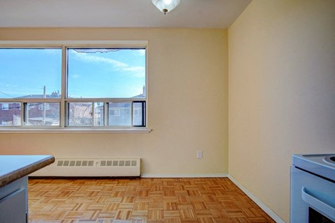 an empty kitchen with a large window and wood flooring