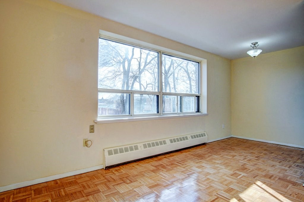 an empty living room with a large window and wooden floors