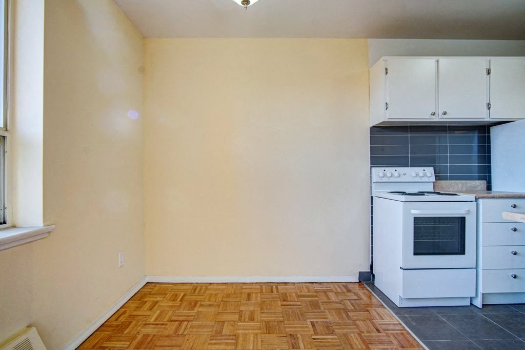 an empty kitchen with white appliances and a wooden floor