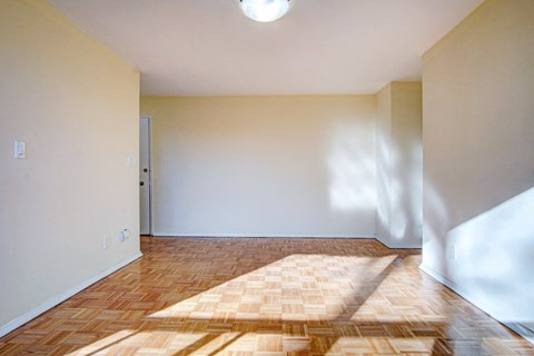 an empty living room with wood floor and white walls