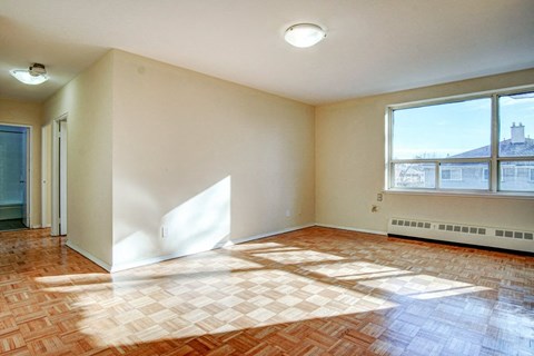an empty living room with a large window and wood floors