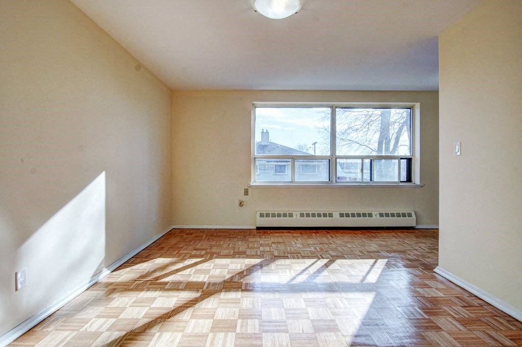 an empty living room with a large window and wooden floors