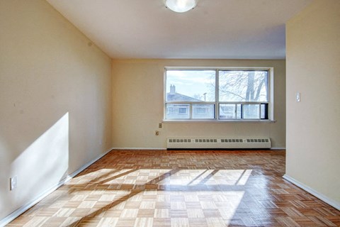an empty living room with a large window and wooden floors