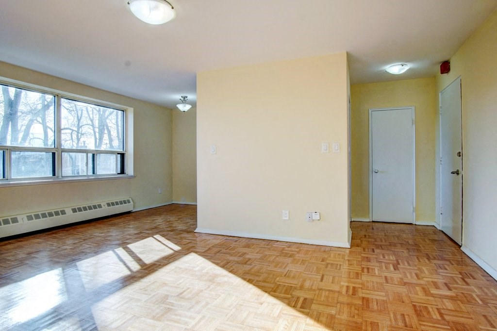 an empty living room with a large window and wooden floors