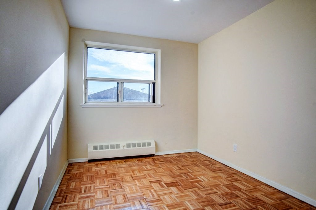 an empty room with a window and wooden floors