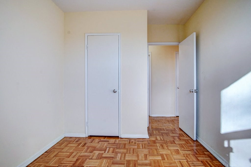 an empty room with three doors and a wooden floor