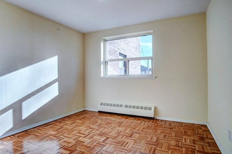 an empty room with a window and wooden floors