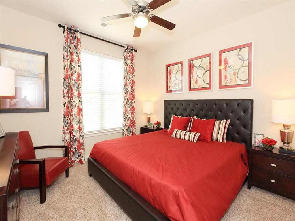 a bedroom with a red bed and a ceiling fan