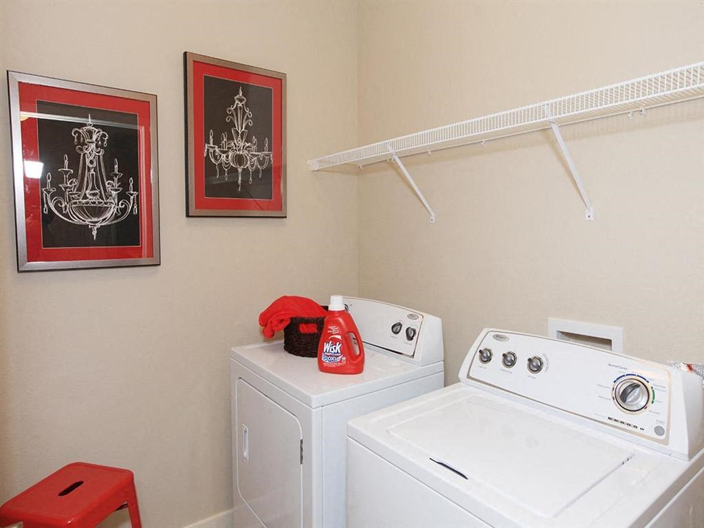 two washers and a dryer in a white laundry room