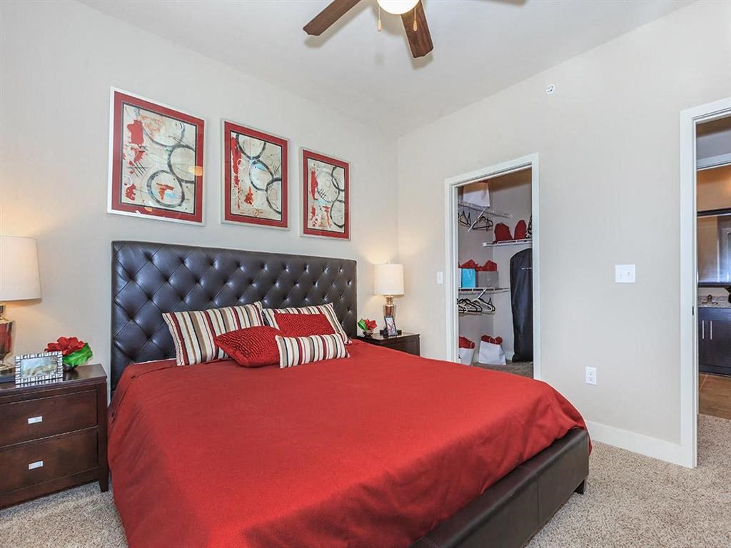 a bedroom with a red bed and a ceiling fan