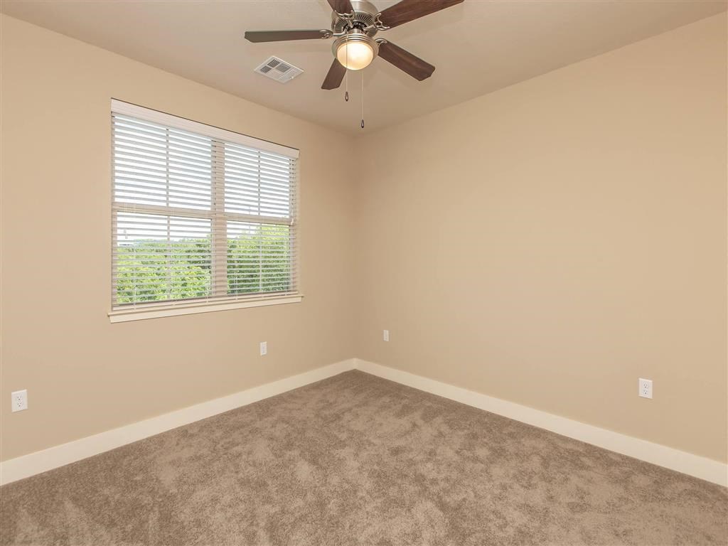 an empty bedroom with a ceiling fan and a window