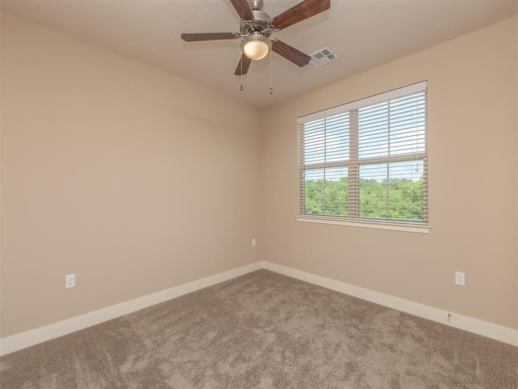 an empty bedroom with a ceiling fan and a window