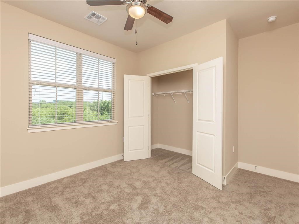 an empty bedroom with a closet and a ceiling fan