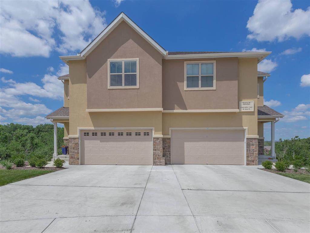 a beige house with two garage doors and a driveway