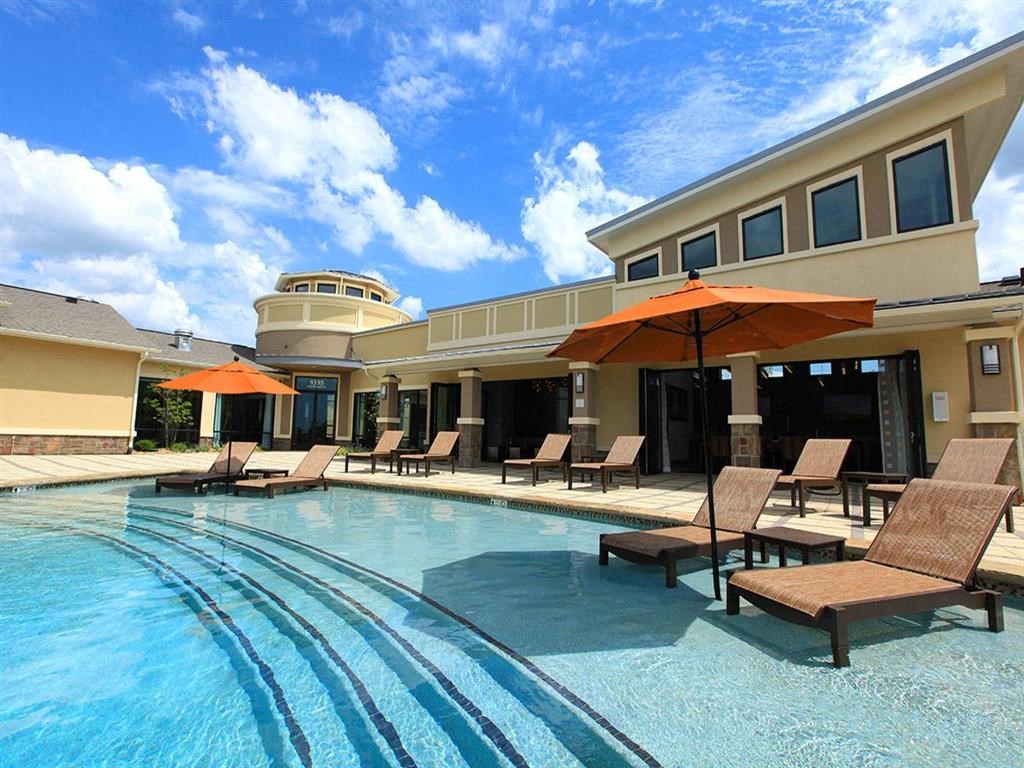 a swimming pool with chairs and umbrellas in front of a building