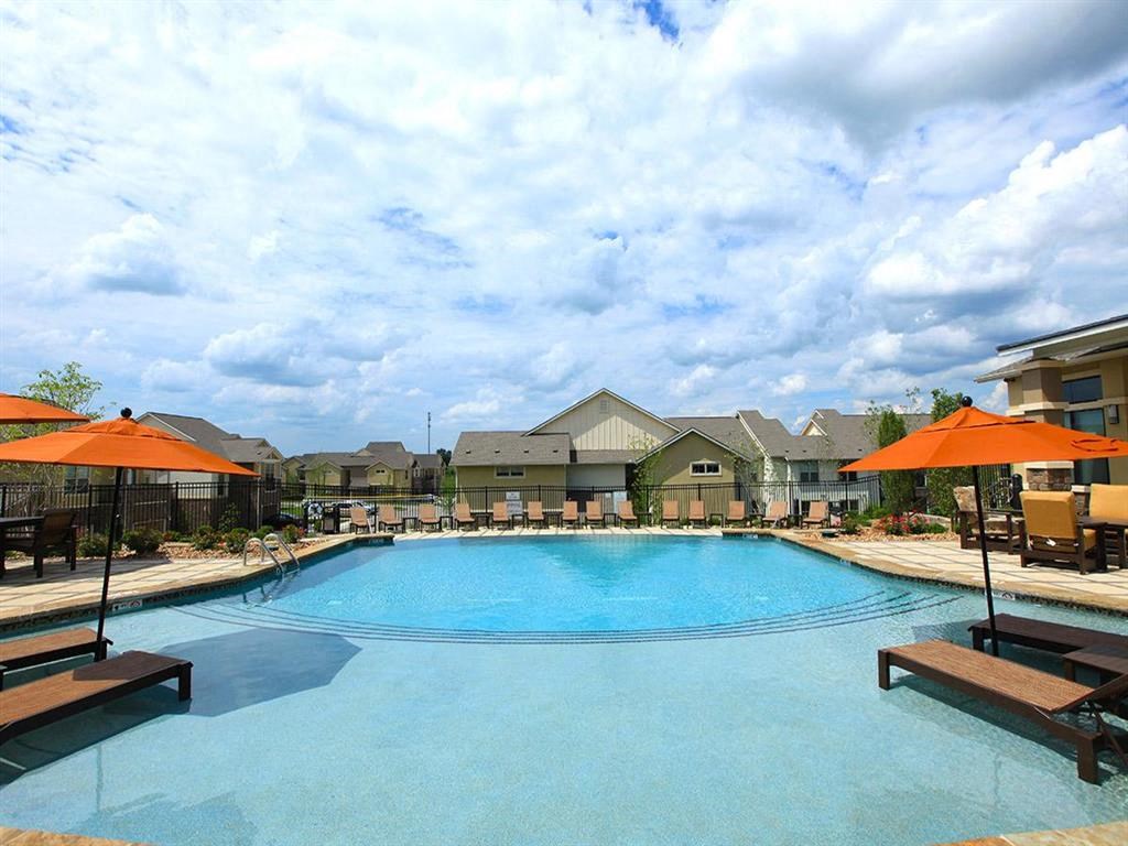 a large swimming pool with umbrellas and buildings in the background