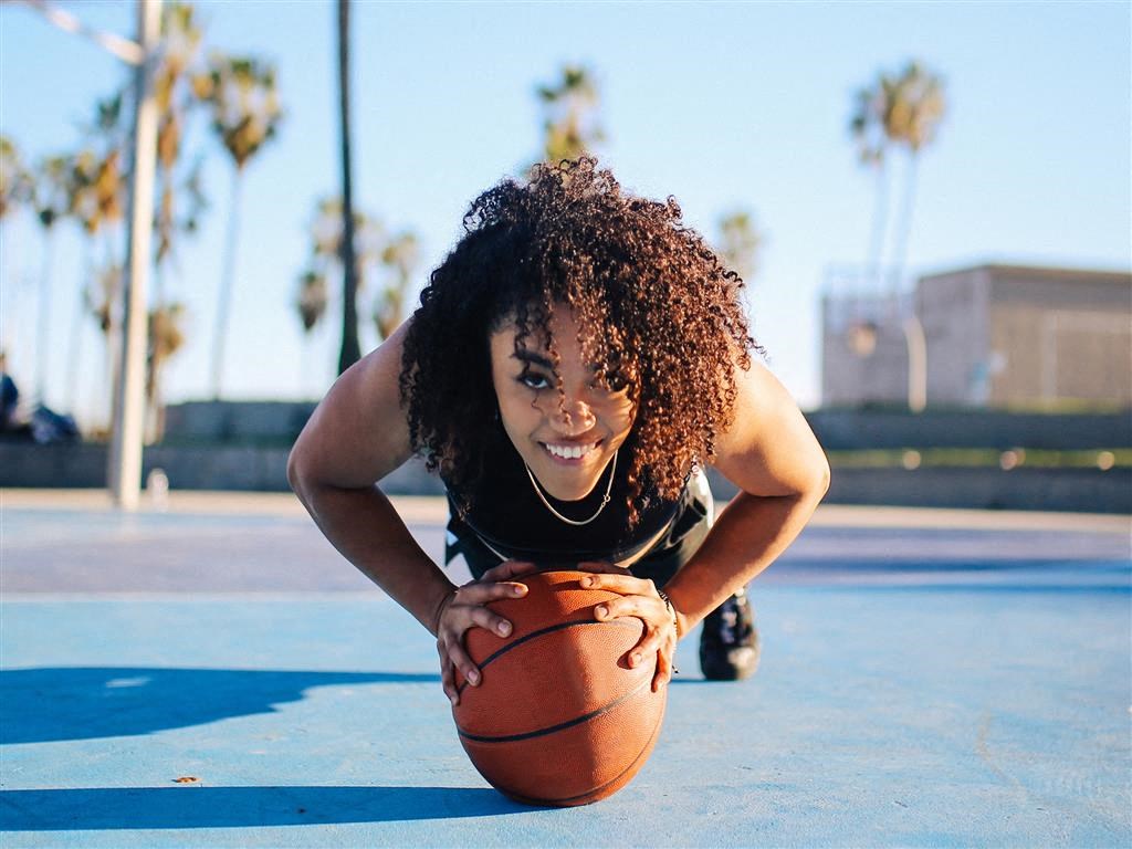 a young woman laying on a basketball on a court
