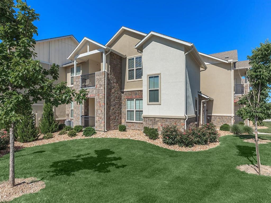 an apartment building with green grass and trees