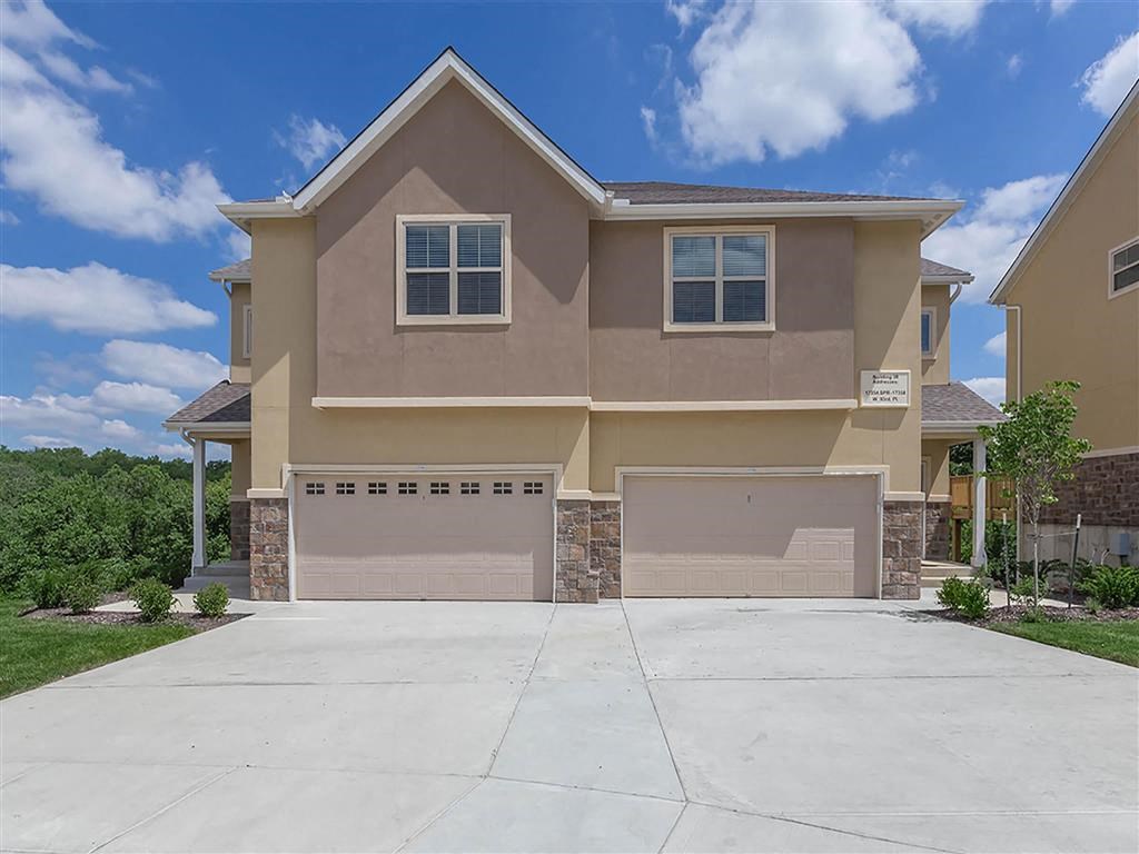 a beige house with two garage doors and a driveway
