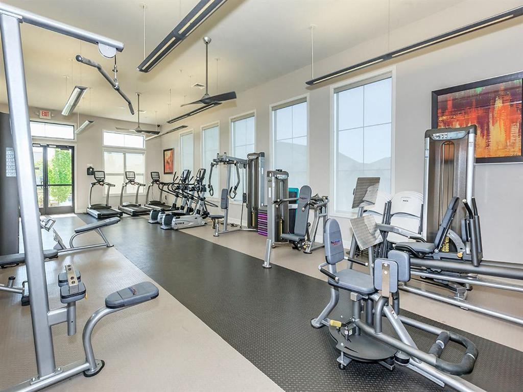 a gym with cardio equipment and windows in a building