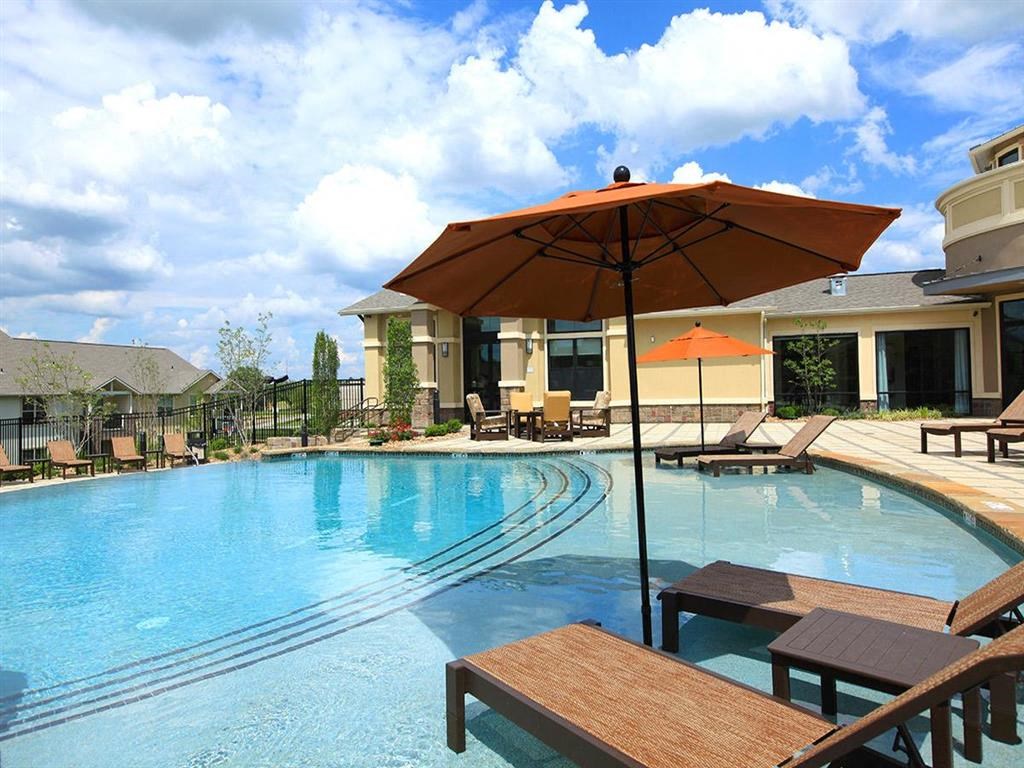 a large swimming pool with chairs and an umbrella
